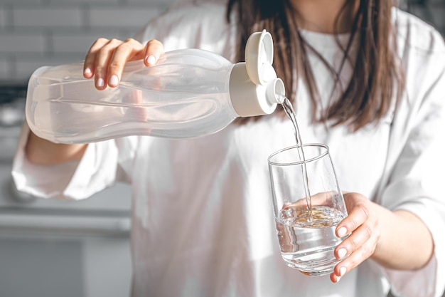 Closeup a woman pours water into a glass