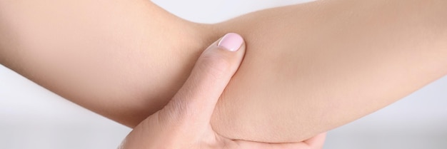 Closeup of a woman pressing the fold of her arm elbow pain joint disease skin care muscle