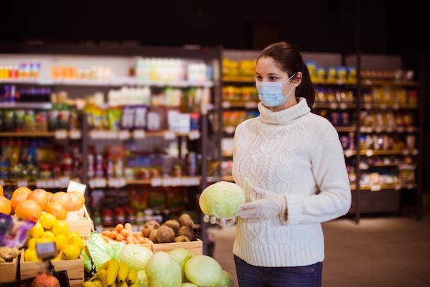 Closeup woman in protective mask and gloves holding fresh cabbage proposing customer to buy local vegetables Eating fresh vegetables in winter to get more vitamins