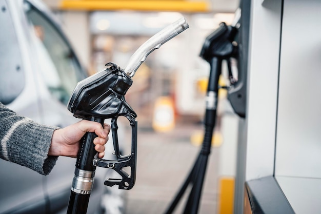 주유소에서 자동차에 휘발유 연료를 펌핑하는 여성의 근접 촬영 가솔린 또는 가솔린이 모터 운송 개념으로 펌핑되고 있습니다.