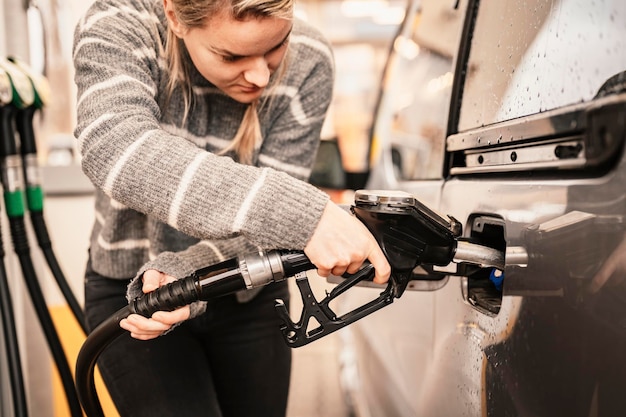 Closeup of woman pumping gasoline fuel in car at gas station Petrol or gasoline being pumped into a motor Transport concept