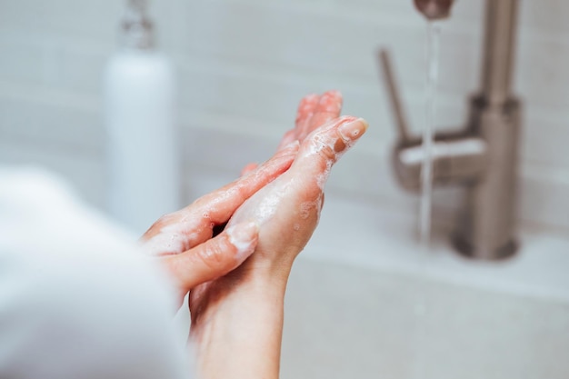 Closeup of woman rubbing hands with a soap in the bathroom