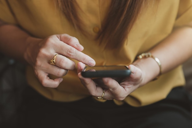 Closeup of a woman's finger holding a smartphone in a coffee shop hipster girl using cell phone dur