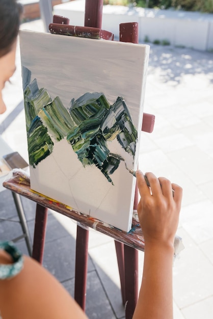 Photo closeup of woman's hand applying paint to a canvas