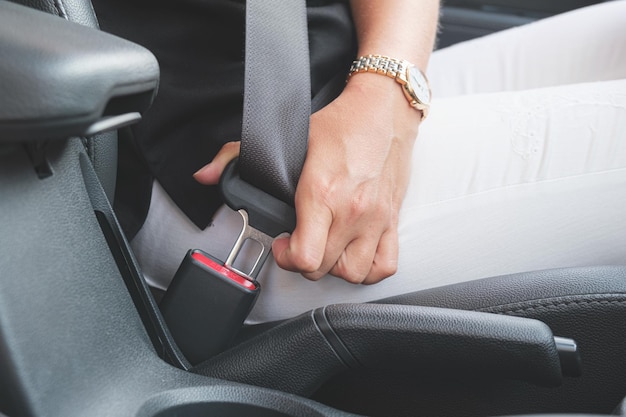 Photo closeup of a woman's hand fastening a seat belt in a car