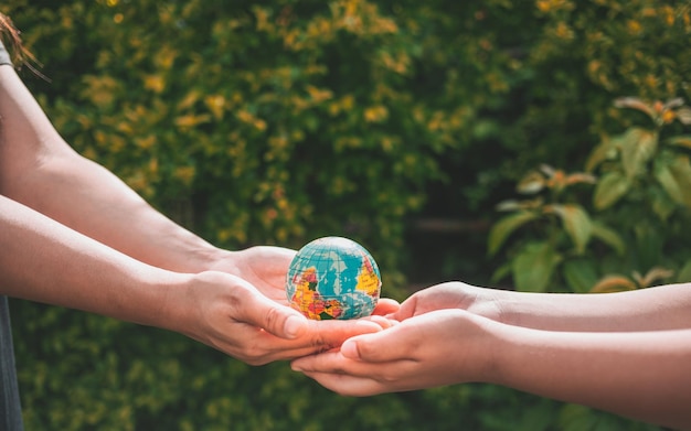 Closeup of woman's hand giving an asteroid world to boy' hands holding planet earth save the earth