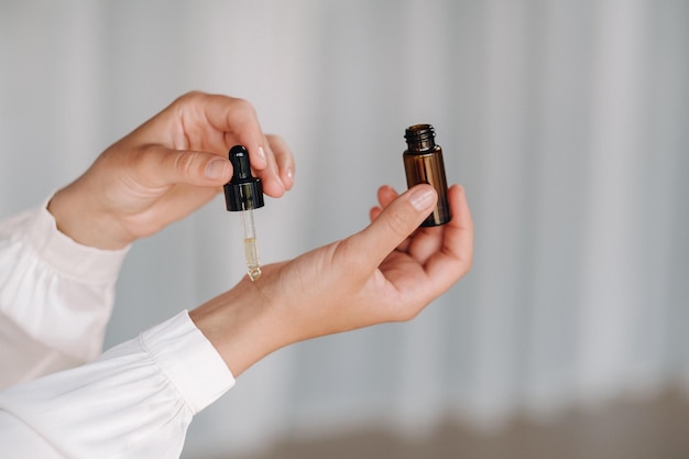 closeup of a woman's hands applying essential oil on her wrist indoors