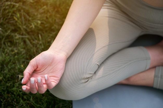 Closeup of a woman's hands on a background of green grass Young woman doing yoga in the park at sunset