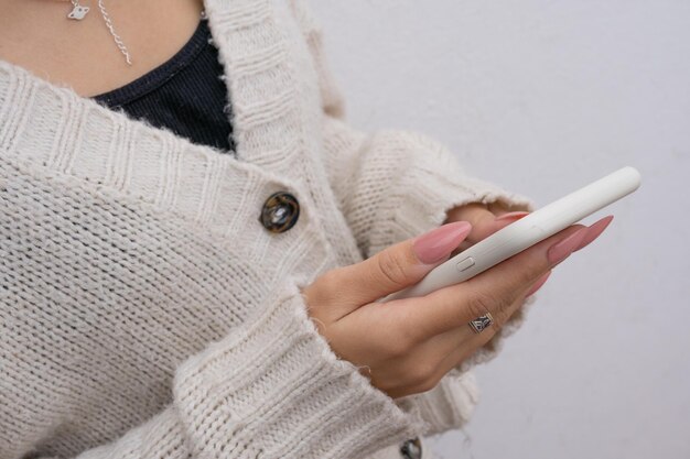 携帯電話を使用してピンクの彫刻が施された爪を持つ女性の手のクローズ アップ