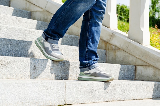 Closeup of a woman's legs in jeans and sneakers going down the stairs