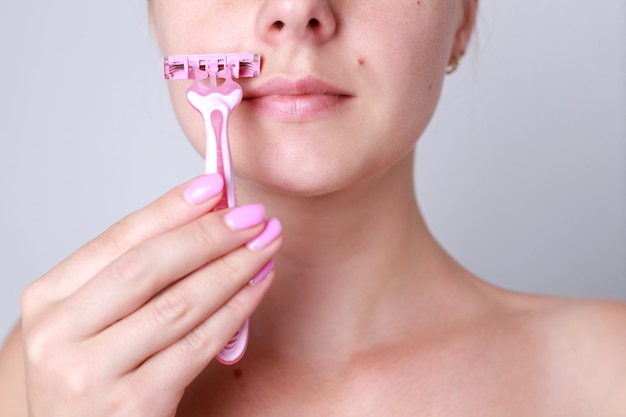 Closeup of a woman shaving her face with a razor face epilation laser epilation of the upper lip of the female