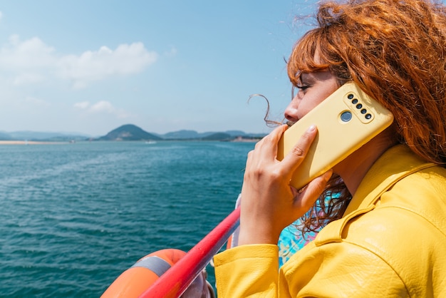 Primo piano di una donna che parla al telefono su una barca in mezzo al mare