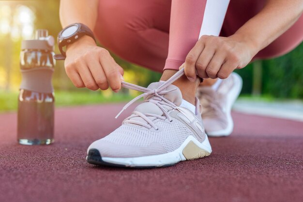 Foto close-up di una donna che lega i lacci delle scarpe una corridore di fitness sportiva che si prepara a fare jogging all'aperto