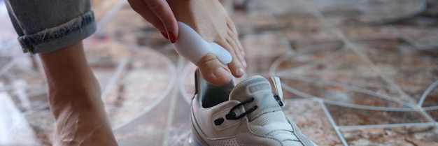 Closeup of woman using brace for hallux valgus and putting on sneaker podiatric medicine and