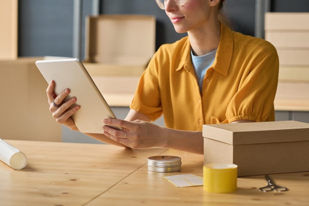 Photo closeup of woman using digital tablet to track parcels online at table