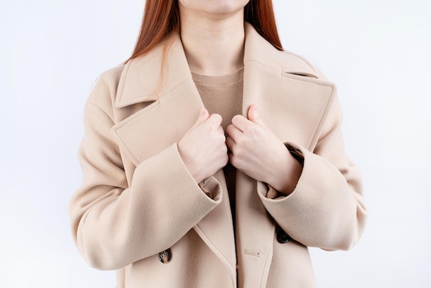 Крупным планом женщина в бежевом пастельном пальто на белом фоне