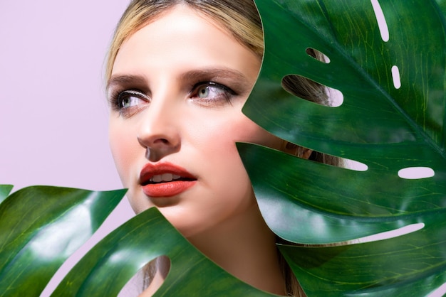 Closeup woman with alluring perfect clean skin holding green leave