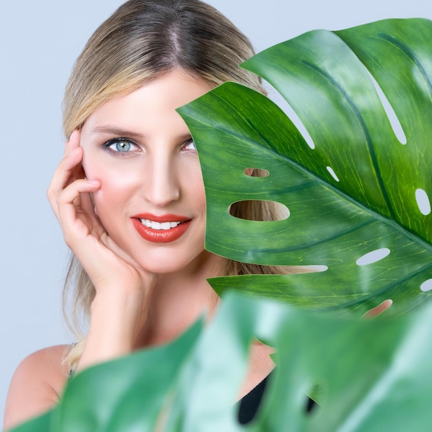 Closeup woman with alluring perfect clean skin holding green leave