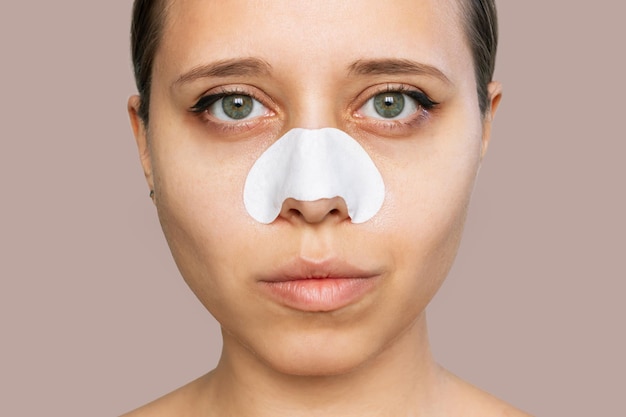 closeup of a woman with cleaning nose strips from blackheads or black dots on her skin