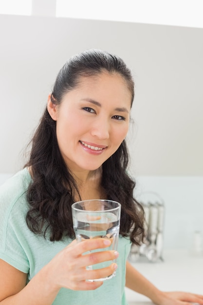 Closeup of a woman with a glass of water in kitchen