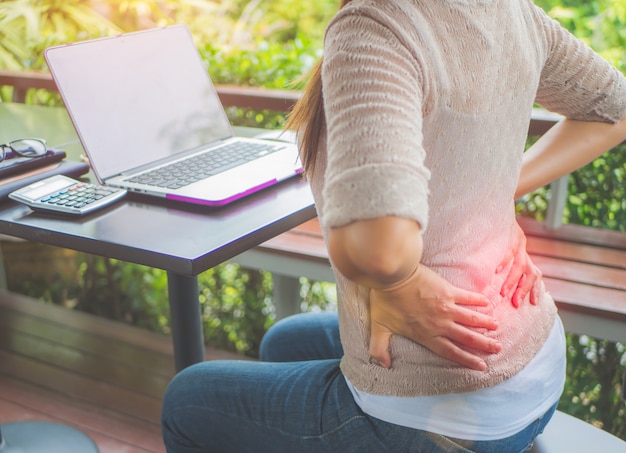 Closeup woman with hands holding her waist back in pain