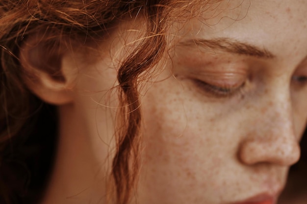 Closeup of woman with red wavy curl on her face looking down