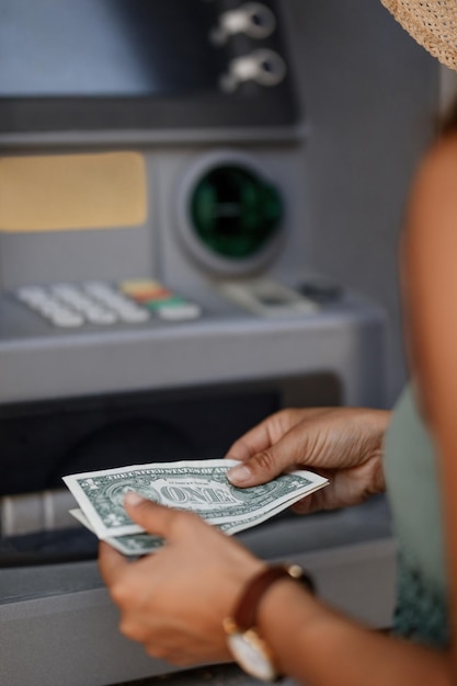 Closeup of woman withdrawing cash from ATM machine