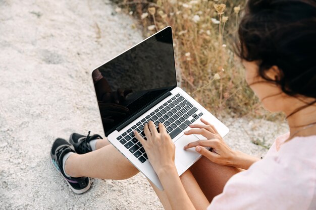 Closeup of woman working on laptop outdoors, at a beach.