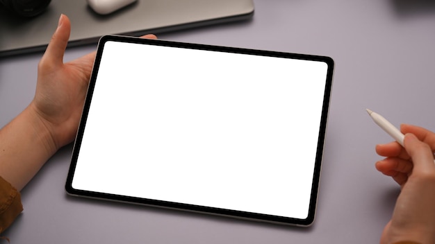 Closeup A woman working on portable tablet touchpad white screen mockup in her trendy purple desk