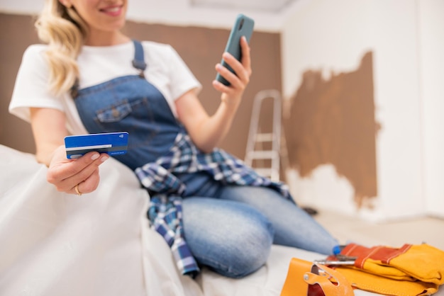 Closeup of a womans hand holding a bank card in the background repair work