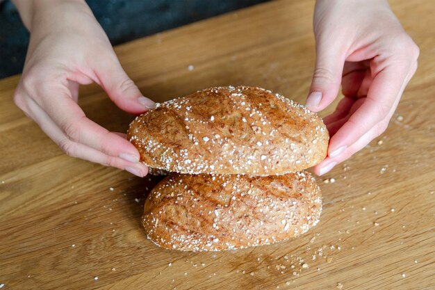 Closeup of womans hands holding two bread pieces on brown table making sandwiches