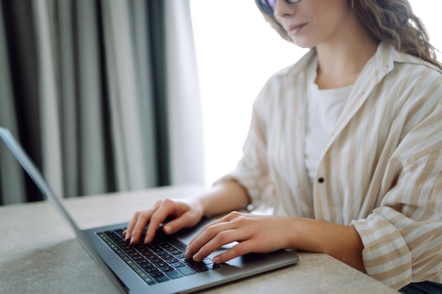 家で現代のラップトップでタイピングしているラップトップキーボードの女性の手のクローズアップ フリーランスのコンセプト