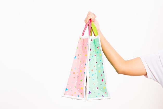 Photo closeup women hand holding colorful multicolor shopping bag many packets isolated on white background female holds in hand white clear empty blank craft paper gift bag shopping day concept