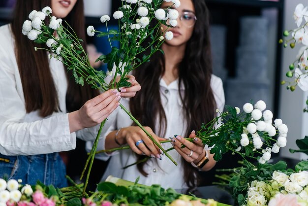 Крупный план женских рук, собирающих и делающих красивые праздничные букеты в уютном цветочном магазине Флористика и изготовление букетов в цветочном магазине Малый бизнес