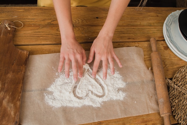 Closeup womens hands draw a heart from flour advertising of a\
bakery or pastry shop