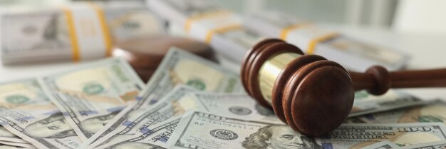 Foto close-up del martello di legno del giudice e un mucchio di dollari sul tavolo frode finanziaria e arbitrato