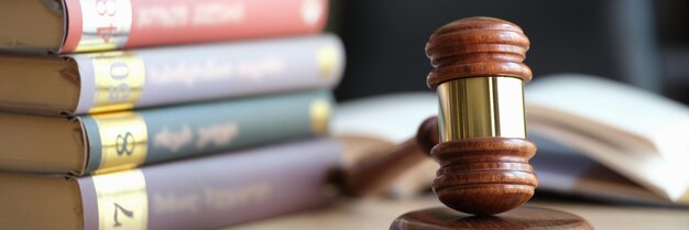 Closeup of wooden judge gavel on sounding block and stack of law books jurisprudence attorney