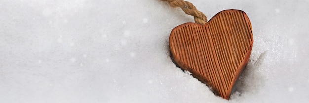 Closeup on wooden shape heart in the snow with copy space at the left