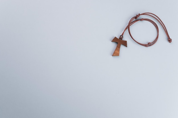 Closeup of a wooden tau cross necklace isolated on a gray background