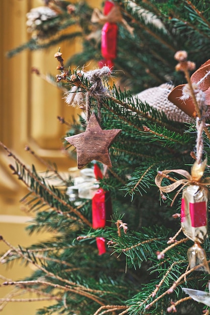 Closeup wooden toy star on Christmas tree branch Handmade Christmas zerowaste ornaments