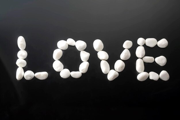 A closeup of the word love written in white rocks on a beach