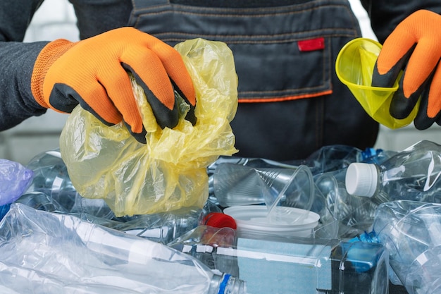 Closeup worker sorts trash on conveyor belt man working in a recycling factory