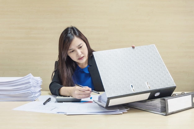 Donna lavoratrice del primo piano che lavora con la carta del lavoro e l'archivio del documento nel concetto del duro lavoro