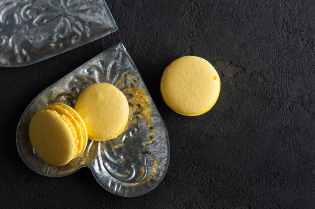 Closeup of yellow macaroons on black concrete