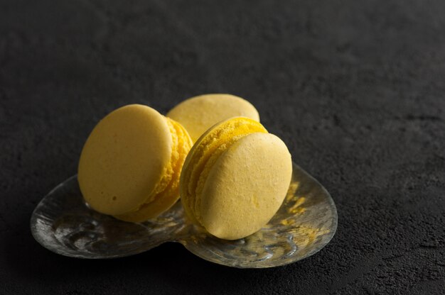 Closeup of yellow macaroons on black concrete