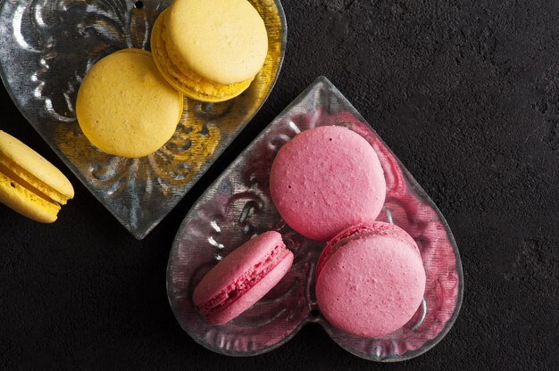 Closeup of yellow pink macaroons on black concrete 