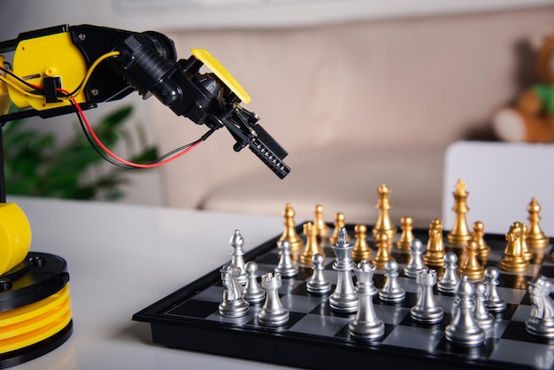 Closeup yellow robot arm playing move chess on chessboard stem education elearning technology science robot education concept