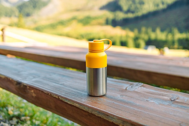 Closeup yellow steel thermos with hot tea coffee in the mountains Copy space Zero waste no plastic