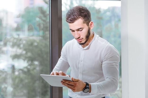 Closeup of young arab ethnency man using tablet pc indoor.