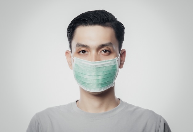 Closeup Young Asian Man wearing hygienic mask to prevent infection, 2019-nCoV or coronavirus. Airborne respiratory illness such as pm 2.5 fighting and flu isolated on white